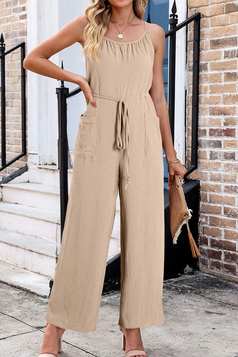 One piece Jumpsuit in beige with spaghetti straps and rounded neck, tied belt at waist, deep pockets and wide legs