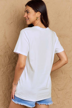 Woman wearing a white t-shirt and denim shorts against a beige wall
