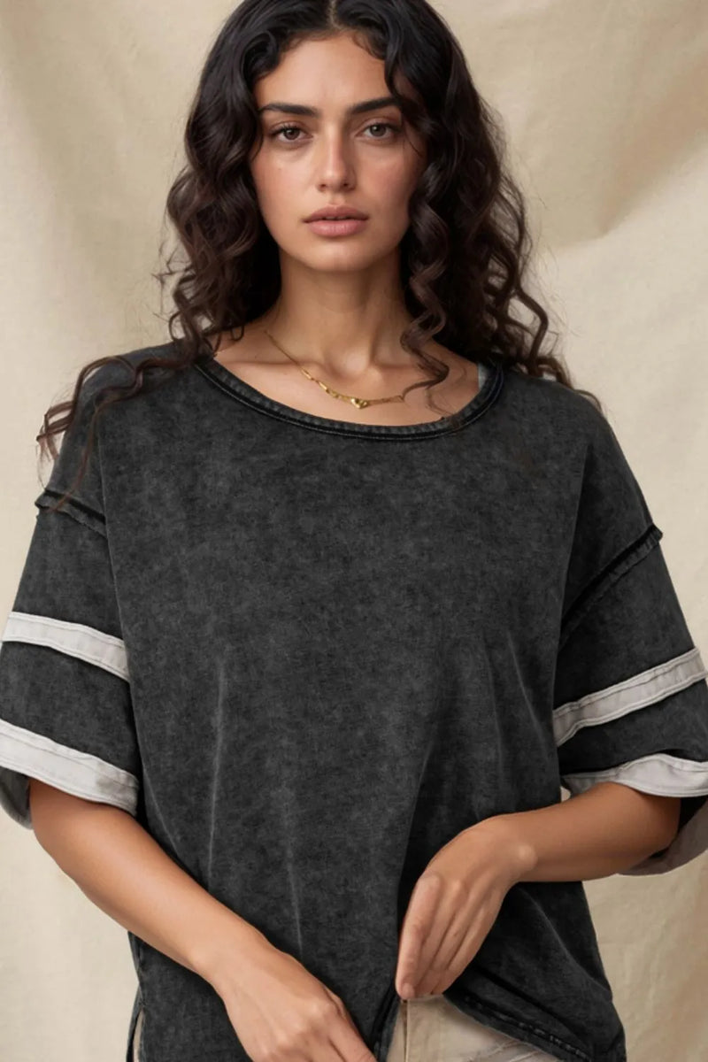 Faded look black tshirt with dropped shoulders and sleeves with two bands of trim in white and scooped neck almost make it look like a football jersey. Exposed seams and long body