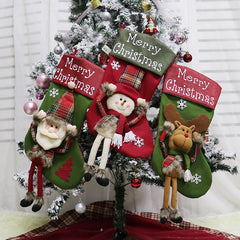 Three Christmas stockings with festive characters in front of a decorated tree.