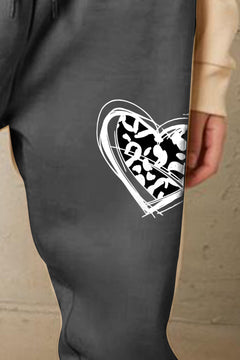 Dark gray pants with a white heart design featuring a pattern on a beige background
