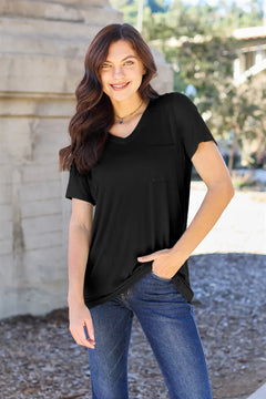 Woman wearing a black t-shirt and blue jeans standing outdoors.