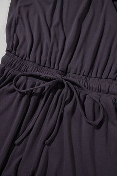 Close-up of a dark purple dress with a tie waist.