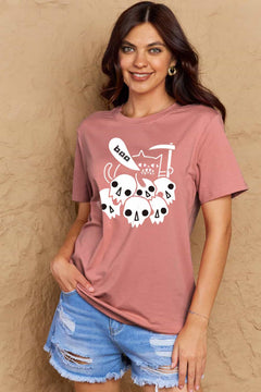 Pink tshirt round neck with short sleeves and Halloween design of 6 white skulls below and outline of a cat saying boo and holding a scythe.