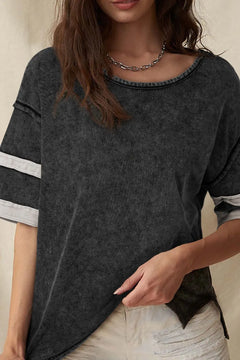 Person wearing a dark gray t-shirt with white stripes on the sleeves against a neutral background