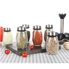 Set of glass spice jars with metal lids on a checkered tablecloth.
