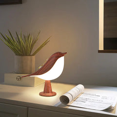 Bird-shaped lamp on a desk with a plant and newspaper in the background