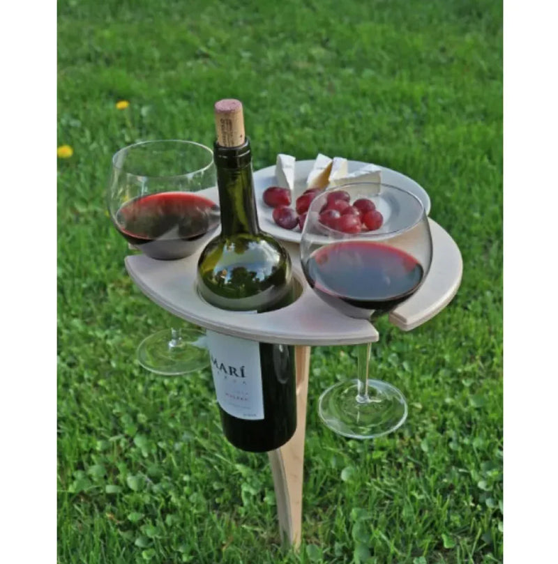 Portable outdoor table with wine bottle and glasses on a grassy background