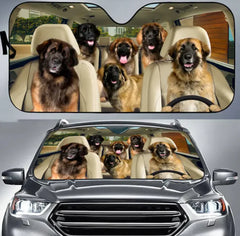 Car sunshade with a design of dogs in a car and a real car with the sunshade applied.