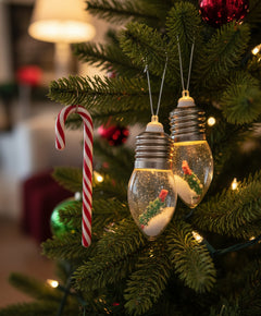 Two light bulbs with small figurines inside on a plain background