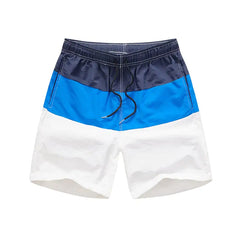 Color-blocked swim shorts with navy, blue, and white sections on a white background