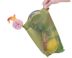 Green clean biodegradable pet waste bag with fruits and a cleaning brush in it to demonstrate the strength