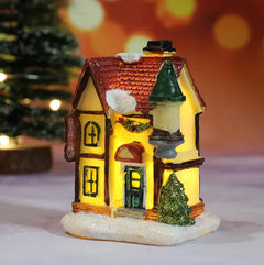 Decorative miniature house with lights on a blurred Christmas tree background