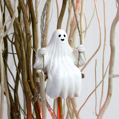 White ghost decoration against a background of branches