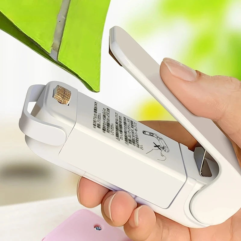 Person holding a white mini heatsealer with a blurred green background