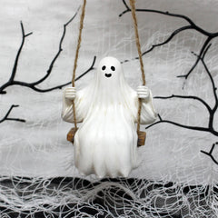 Ghost on a swing against a Halloween-themed background with branches and spider webs.