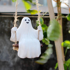 White ghost figurine on a swing with greenery in the background