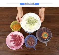 Four silicone food covers with different food items on a wooden surface