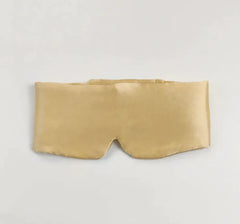 Gold silk sleep mask on a light gray background