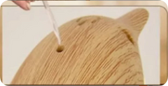 Wooden surface with a hole being filled with white substance, possibly glue or filler.
