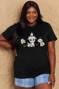 Woman wearing a black t-shirt with a cat in a witch hat and pumpkins design, standing against a beige wall.