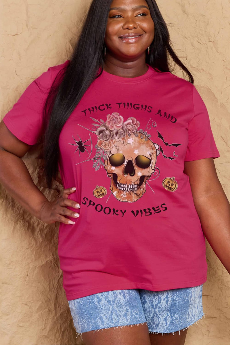 Pink t-shirt with a skull surrounded by small Jackolanterns, batts, flowers and a spider. The text Reads Thick Thighs and Spooky Vibes
