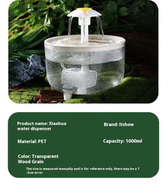 Cat water fountain with water flowing, surrounded by greenery clear bowl with white fountain head shaped like a daisy. 