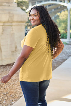 Woman wearing a yellow t-shirt and blue jeans standing outdoors.