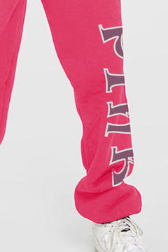 Pink drawstring sweat pants with pockets and the word PINK going down the left leg from knee to ankle in brownish letters outlined in white.