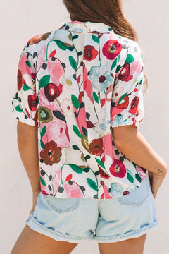 Women's white blouse with bold red, pink, and white flowers blooming. paired with denim shorts