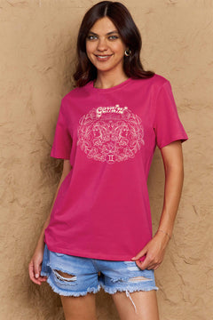 Pink tshirt with round neck and short sleeves, design is all in pink with Gemini above two long haired twins facing away from each other and encircled by a wreath of flowers and leaves.At the bottom of the design is a circle with Roman numeral Two in it.