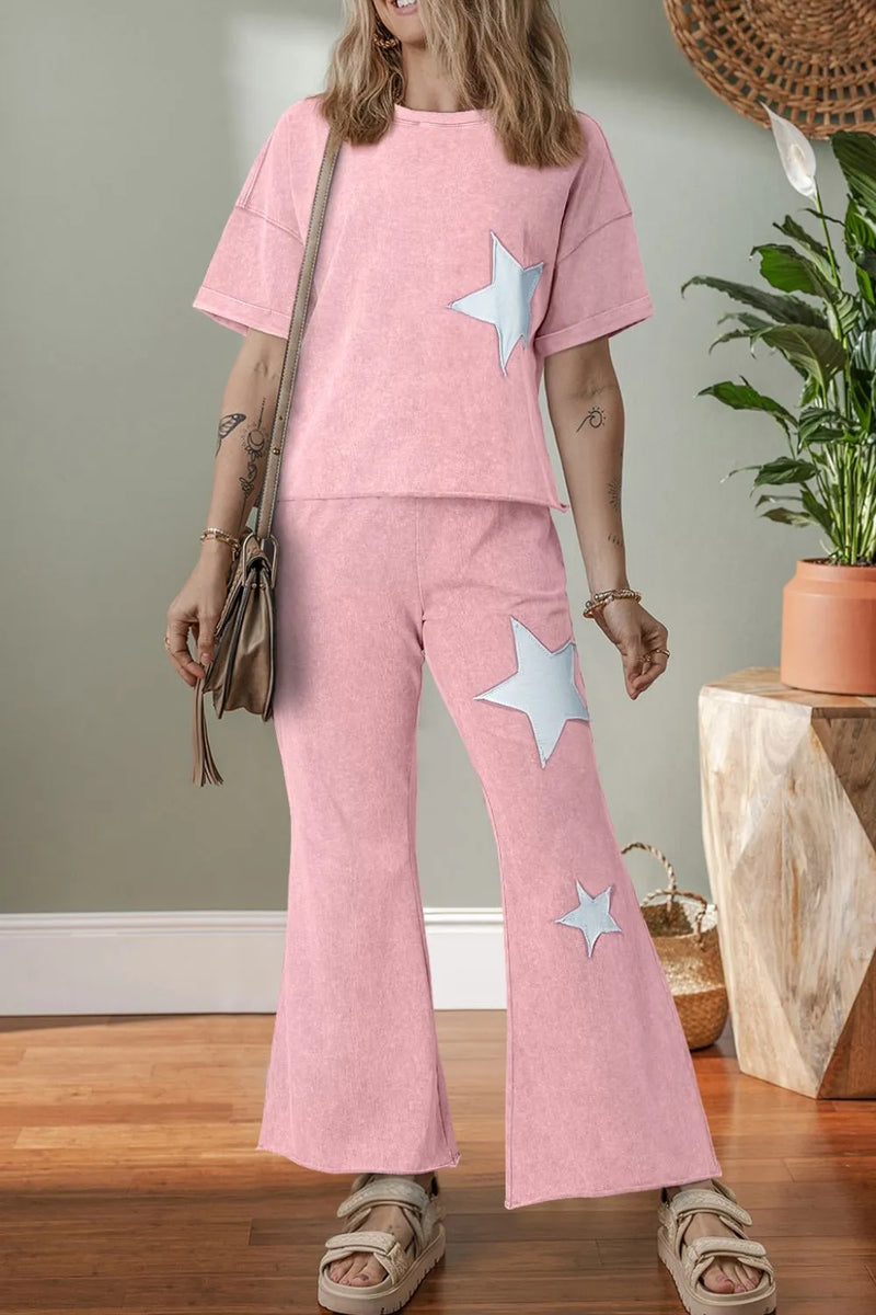 Dropped shoulder pink tshirt with silver star and matching pants with two stars going down the leg on same side as the star on the shirt, and boot cut bottoms.