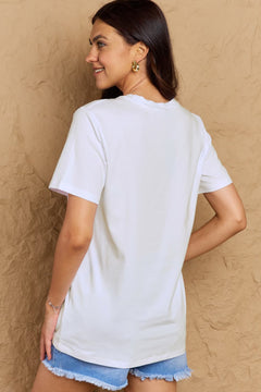 Woman wearing a white t-shirt and denim shorts against a beige wall