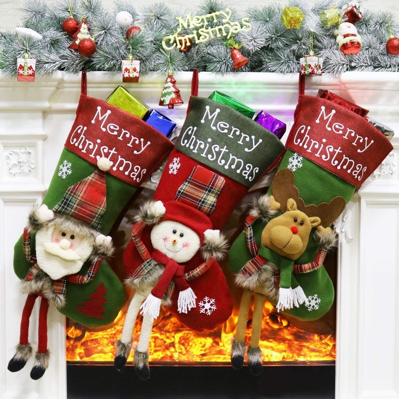Three Christmas stockings with festive designs hanging by a fireplace.