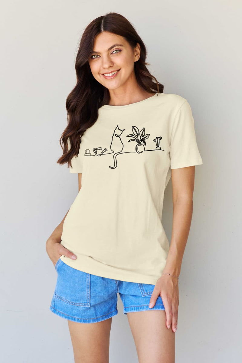 Creamy Tshirt with simple graphic design on front. One long line of black ink outlines a cat sitting on a wall with plants and a watering can. Short sleeves, round neck