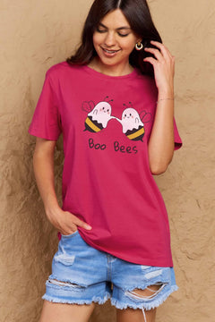 Person wearing a pink t-shirt with 'Boo Bees' design against a beige wall.