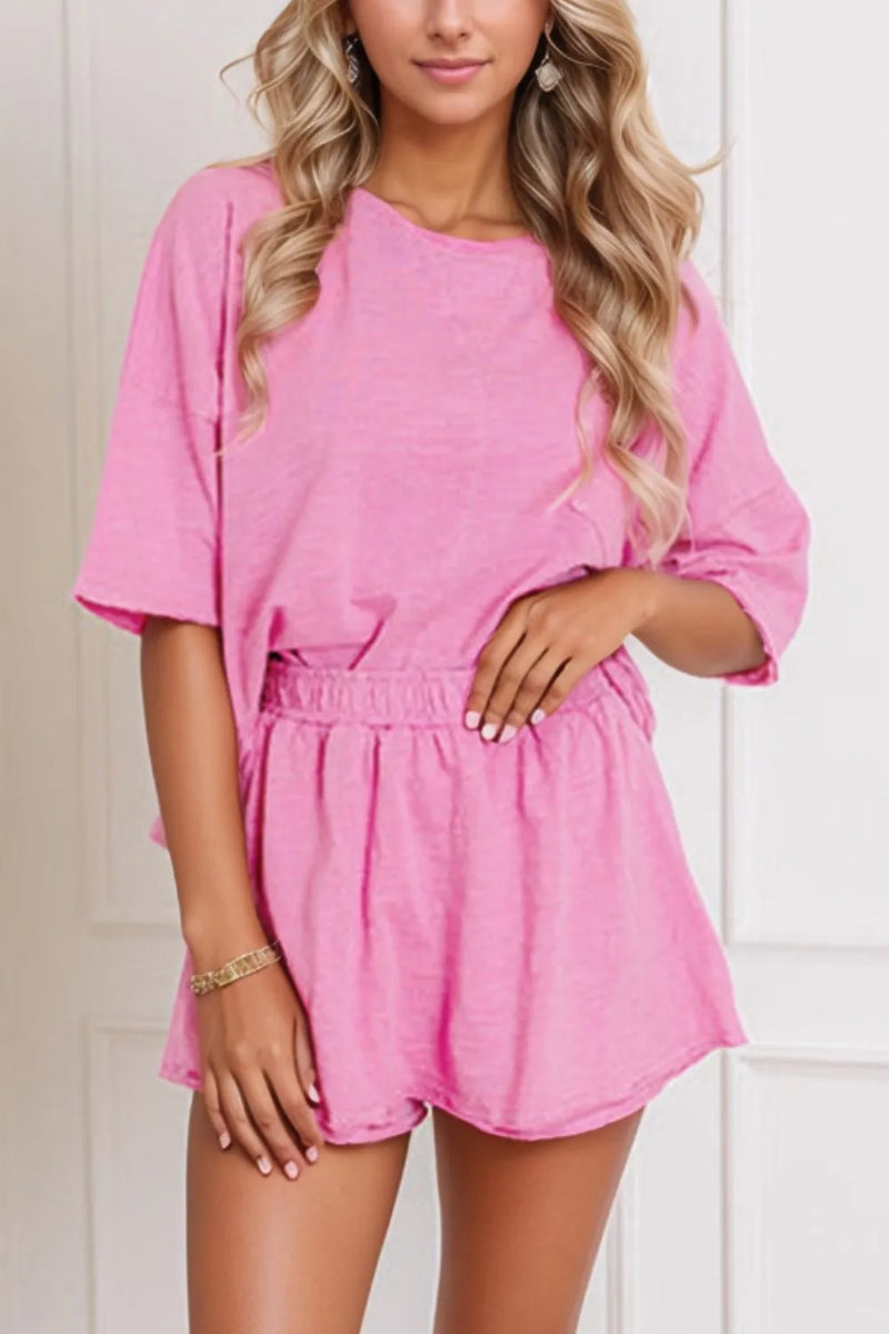 Woman wearing a pink matching shorts and shirt set with round neck and three quarter length sleeves.