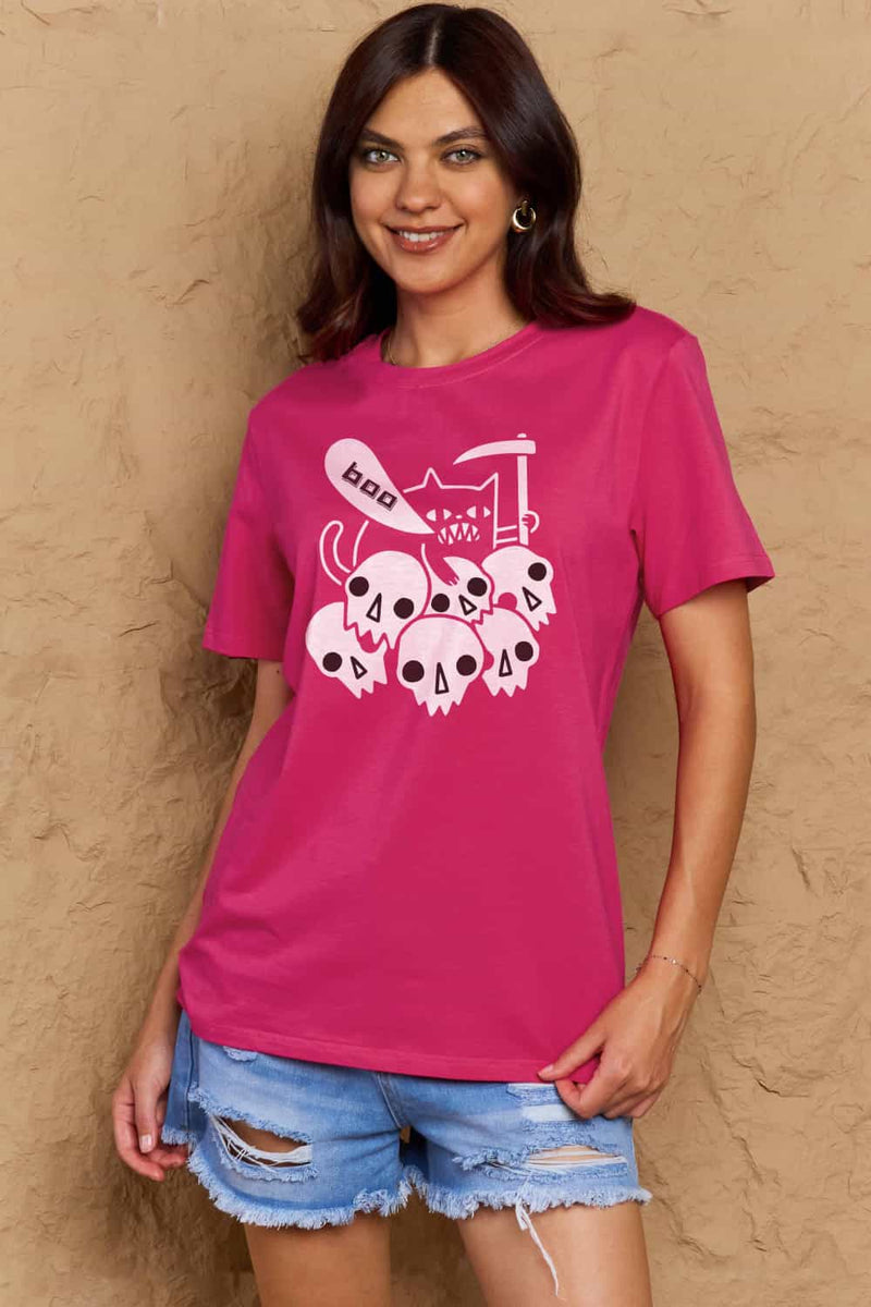 Bright pink tshirt round neck with short sleeves and Halloween design of 6 white skulls below and outline of a cat saying boo and holding a scythe.