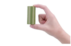 Hand holding a cylindrical green roll of biodegradable pet waste bags against a white background