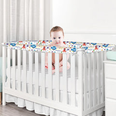 Baby in a crib with a colorful bumper pad