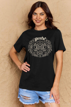 Black tshirt with round neck and short sleeves, design is all in pink with Gemini above two long haired twins facing away from each other and encircled by a wreath of flowers and leaves.At the bottom of the design is a circle with Roman numeral Two in it.