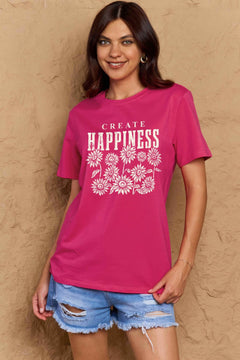 Pink Tshirt with round neck and short sleeves, the caption in capital letters says CREATE HAPPINESS, with create being in small letters centered over Happiness. underneath the letters, in white as well, ten flowers arranged in three rows.