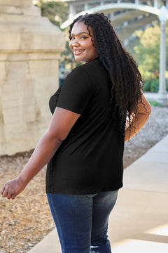Woman wearing a black t-shirt and blue jeans standing outdoors.