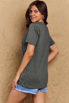 Woman wearing a gray t-shirt and denim shorts against a beige wall