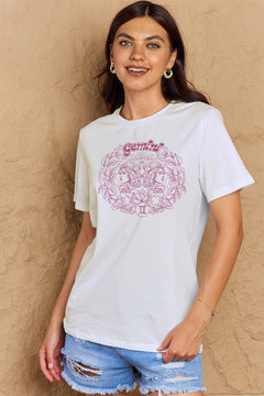 White tshirt with round neck and short sleeves, design is all in pink with Gemini above two long haired twins facing away from each other and encircled by a wreath of flowers and leaves.At the bottom of the design is a circle with Roman numeral Two in it.