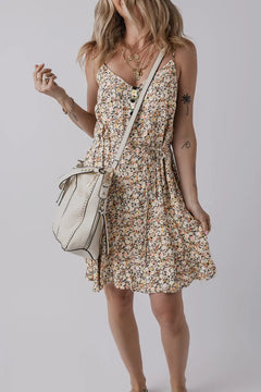 Spaghetti strap v neck with three black buttons onfront, thin cord tie at waist and full skirt that ends above the knee. Pattern is floral with many tiny flowers of cream, yellow, peach, pink and orange, with hints of greenery