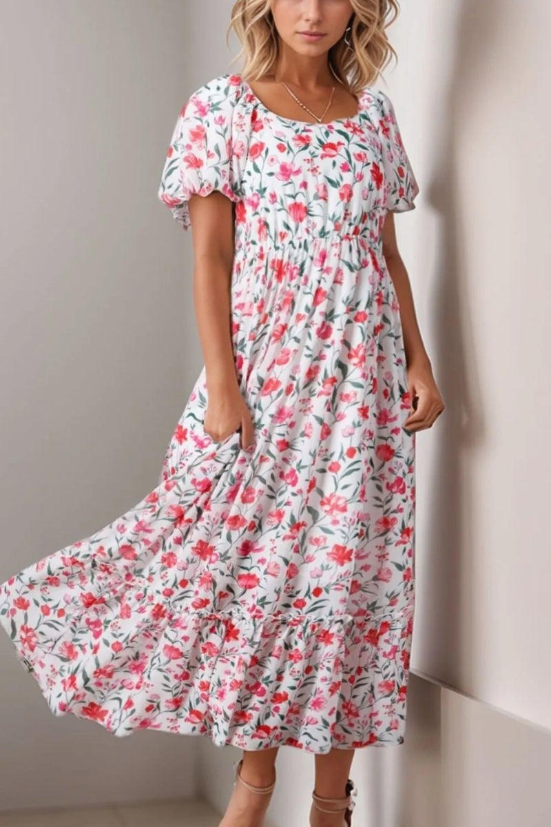 Floral Short Puff Sleeve Tiered Dress with wide round neck and high waist. White background with different sizes and types of pink flowers all over it. Some dark pink and some light, some in full bloom, some budding out. Green leaves and stems.