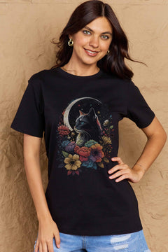 Black tshirt with short sleeves, round neck and styized design of long haired cat with blue eyes surrounded by blooming flowers with the glow of a sliver moon in the background