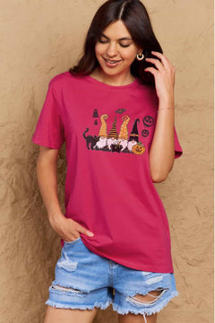 Pink t-shirt with Halloween-themed graphics. Four gnomes sitting behind a caldron with green brew bubbling out, a black cat with arched back on the right and a grinning jack o'lantern on the left with black 'sheet' ghosts, a bat and two black jack o' lantern silhouttes hovering above. Each gnome has a long pointy hat in either orange, black, or a combination of the two. The gnome on the left has a witch hat.