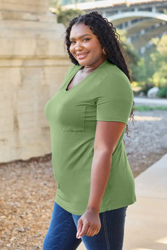 Woman wearing a green shirt standing outdoors with a blurred background